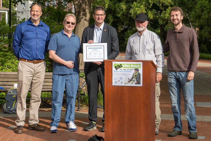 Matt Meyer standing behind a podium with the others which holding the award certificate