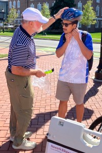 photo of Bob McBride helping fit a UD student with a new helmet